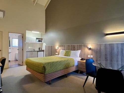 a bedroom with a bed and a table in a room at Airport Manor Inn in Auckland
