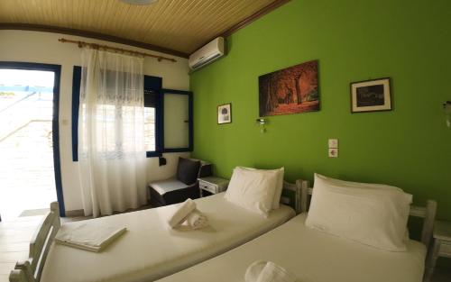 a bedroom with two beds and a green wall at Studios Ntina in Alyki
