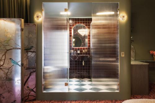 a shower with a glass door with a checkered floor at Medusa Hotel Sydney in Sydney
