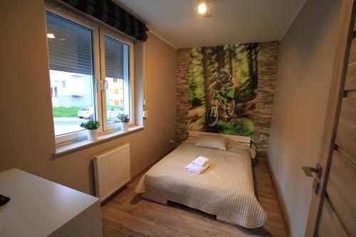 Habitación pequeña con cama y pintura en la pared en Apartament Nowoczesny en Świeradów-Zdrój