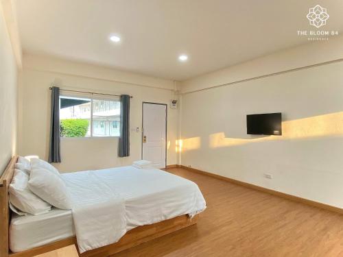 a bedroom with a bed and a flat screen tv at The Bloom 84 Residence in Ban Om Yai