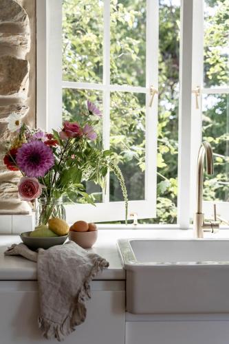 a kitchen sink with a vase of flowers and a window at Stone Gate Cottage in Aldgate