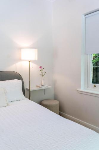 a bedroom with a white bed with a lamp and a window at Stone Gate Cottage in Aldgate