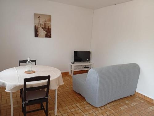 La Celle-sous-GouzonにあるMaison 1- entre ville et verdureのテーブル、椅子、テレビが備わる客室です。