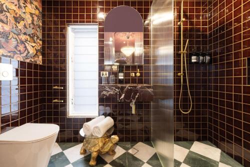 a bathroom with a toilet and a shower with black tiles at Medusa Hotel Sydney in Sydney