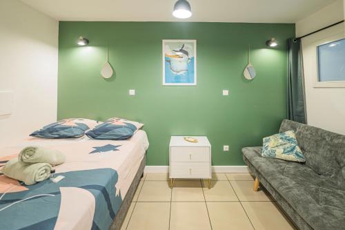 een slaapkamer met een bed en een bank bij Le Nid - Cosy Plage & Confort - Wiskeys in Saint-Paul