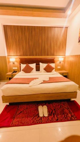 a bedroom with a large bed with two shoes on a rug at Hotel Almora BY The ELEVATE Group Near Delhi INTERNATIONAL Airport WIth- Free AIRPORT Pickup in New Delhi