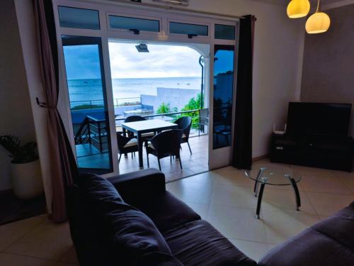 a living room with a couch and a table and a balcony at Baywatch Apartment in La Gaulette