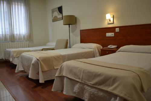a hotel room with three beds and a chair at Apartahotel FC Catedral in León