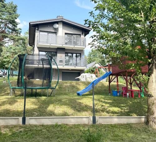 a playground in front of a house with a slide at Dom domek całoroczny Porost nad jeziorem do wynajęcia do 8 osób in Bobolice
