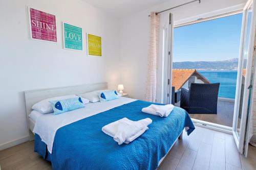een slaapkamer met een blauw en wit bed en een groot raam bij Vila Perla Slatine in Slatine