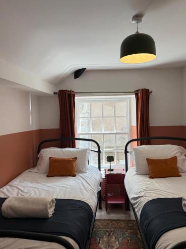two beds in a room with a window at Bow Alley Lodge in Alnwick
