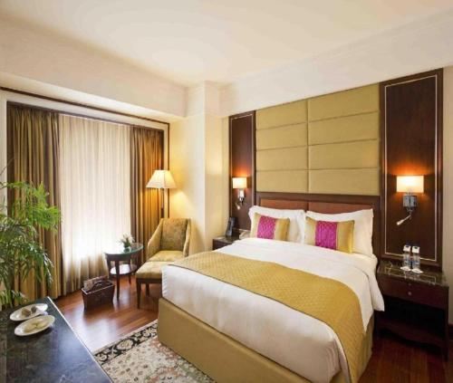 a hotel room with a large bed and a chair at Hotel Hampton International Near Delhi Airport in New Delhi