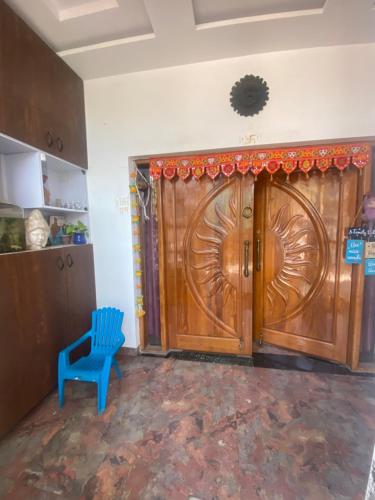 a large wooden door in a room with a blue chair at Aatri Estate in Jabalpur