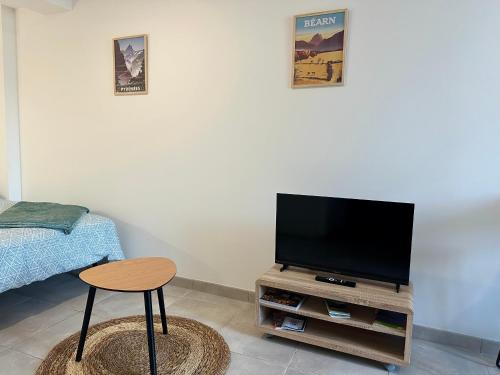 a living room with a tv and a table and a stool at Studio Cosy en vallée d'Ossau in Izest
