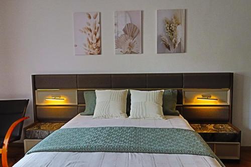 een slaapkamer met een groot bed met drie schilderijen aan de muur bij Ana's home in Sibiu