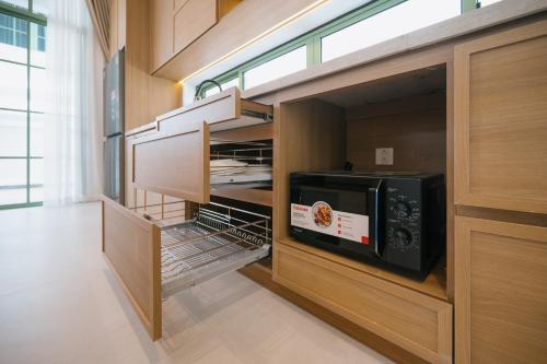 a kitchen with wooden cabinets and a microwave oven at La isla Apartments & Villas - Sea View & Fireworks Phu Quoc in Phu Quoc