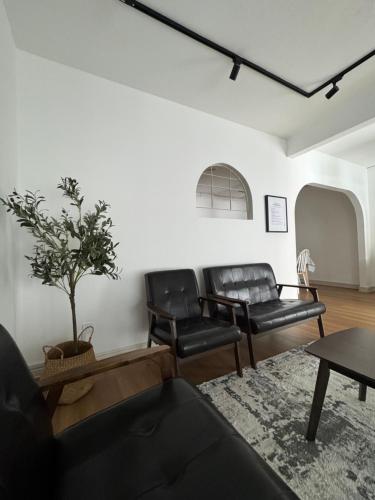 a living room with two black leather chairs and a table at Homestay Rumah Kolek, Shah Alam in Shah Alam