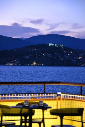a balcony with a table and chairs next to the water at Park Lakeside Ohrid in Ohrid