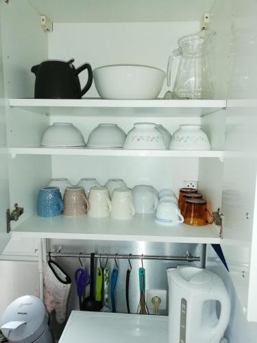 a shelf filled with dishes and other kitchen utensils at Kerguil-léon maison familiale 2 chambres, plages à 10 min en voiture in Moëlan-sur-Mer