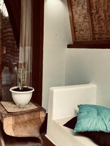 a plant in a pot on a table next to a bed at Rising Sun Bungalows in Gili Meno