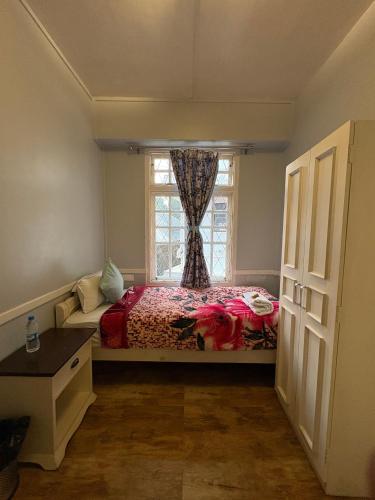 a small bedroom with a bed and a window at Silversky Guesthouse - Shillong in Shillong