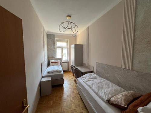 a small bedroom with two beds and a chair at Near Schönbrunn I 1 Min to U6 Niederhofstraße in Vienna