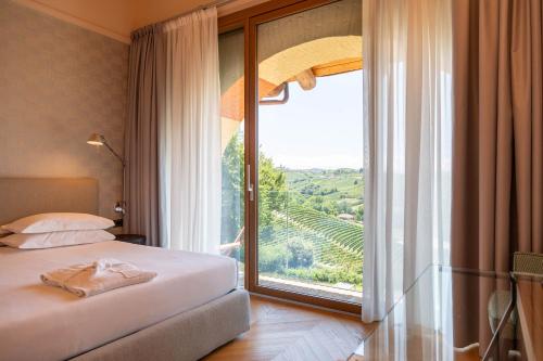 a bedroom with a bed and a large window at Villaggio Narrante - Cascina Galarej in Serralunga d'Alba