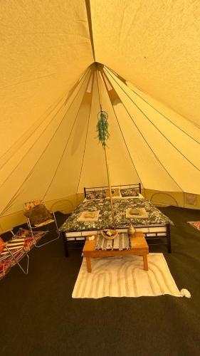 a tent with a bed and a table in it at Glamping Hive by Stream 