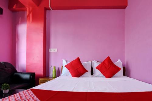 a bedroom with a bed with red and white pillows at Hotel O Chewang Homestay in Darjeeling