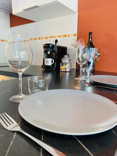 a white plate sitting on a counter with wine glasses at La Perle - Jacuzzi - Wifi - Parking PV in Lunel