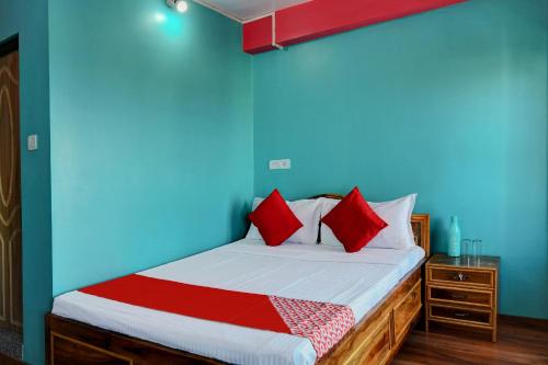 a bed with red pillows in a blue room at Hotel O Chewang Homestay in Darjeeling
