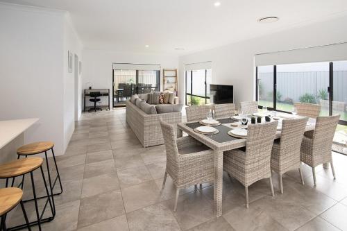 a dining room and living room with a table and chairs at Makin Memories Ducted heating cooling, WIFI, PS4 in Busselton