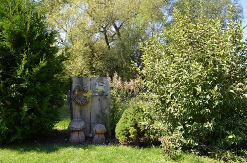 a wooden object in the grass next to some bushes at Ferienwohnungen Holder in Anhausen