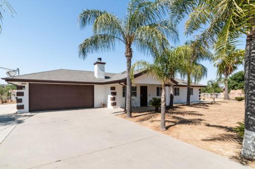 a house with palm trees in front of it at Remodeled 1 Acre Ranch Home in Madera in Madera