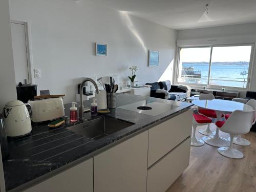 a kitchen with a sink and a counter with chairs at Appartement Design IX - Port du Rosmeur - Sublime Vue Mer - Parking in Douarnenez
