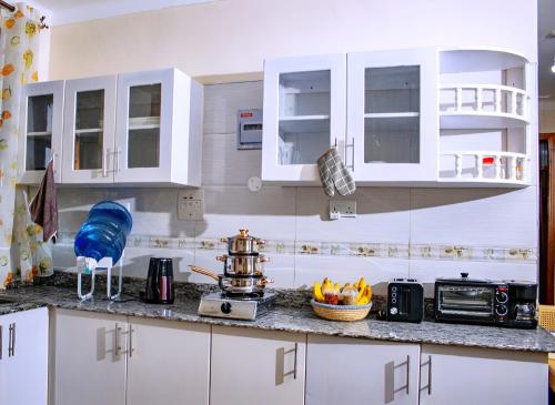 a kitchen with white cabinets and a stove in it at 2BR Morden Apartment Near Soroti Flying Sch - A3 in Soroti
