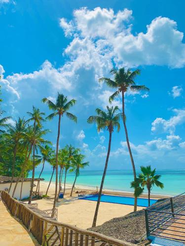 a beach with palm trees and the ocean at Royal Mandarin Hotel & Resort in Pwani Mchangani