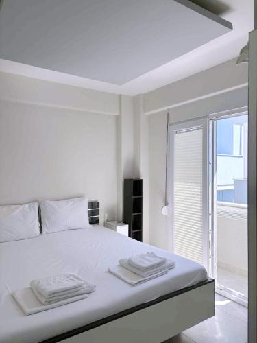 a white bedroom with a bed with towels on it at Anesis in Néa Péramos