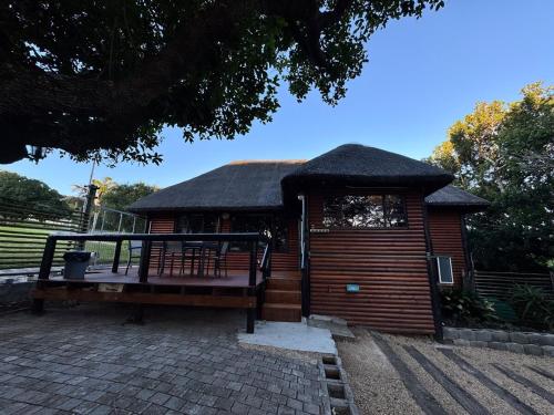 a small wooden building with a roof at The Whispering Milkwood Cottage in Gqeberha