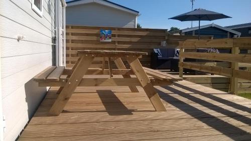 a wooden picnic table on a deck with an umbrella at Vakantie Chalet Makkum in Makkum