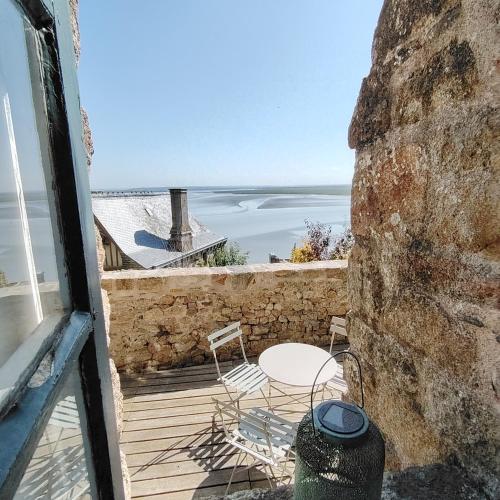 a balcony with a table and chairs and the ocean at Chez Adèle, au pied de l'Abbaye in Le Mont Saint Michel