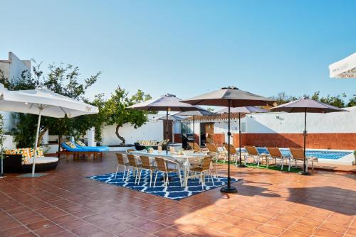 a patio with a table and chairs and umbrellas at Hevres El Capricho in Málaga