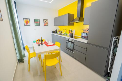 a kitchen with a white table and yellow chairs at Colorama Home in Catania
