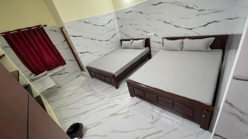 two beds in a room with white marble floors at RR Residency in Vishāram