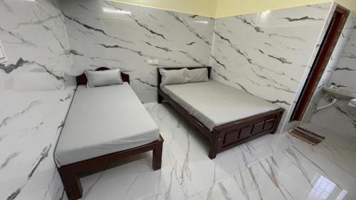 two twin beds in a room with marble walls at RR Residency in Vishāram