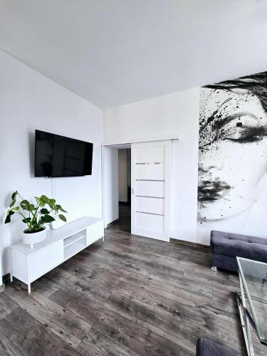 a white living room with a tv and a couch at BoleslaviaApartments - Apartament Starówka 1 in Bolesławiec