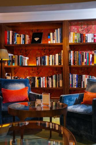 a library with two couches and a table and books at The Merchant House in Manama