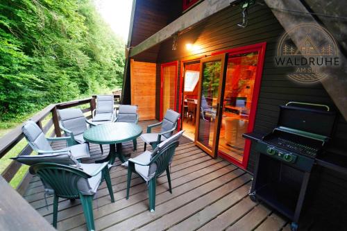 eine Terrasse mit einem Tisch, Stühlen und einem Grill in der Unterkunft Waldruhe 37 inkl Bettwäsche und Handtücher, schlüsselloser Self-Check-in in Bad Arolsen