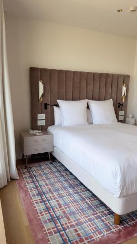 a bedroom with a large white bed and a table at Elkonin Tel Aviv - MGallery Hotel Collection in Tel Aviv
